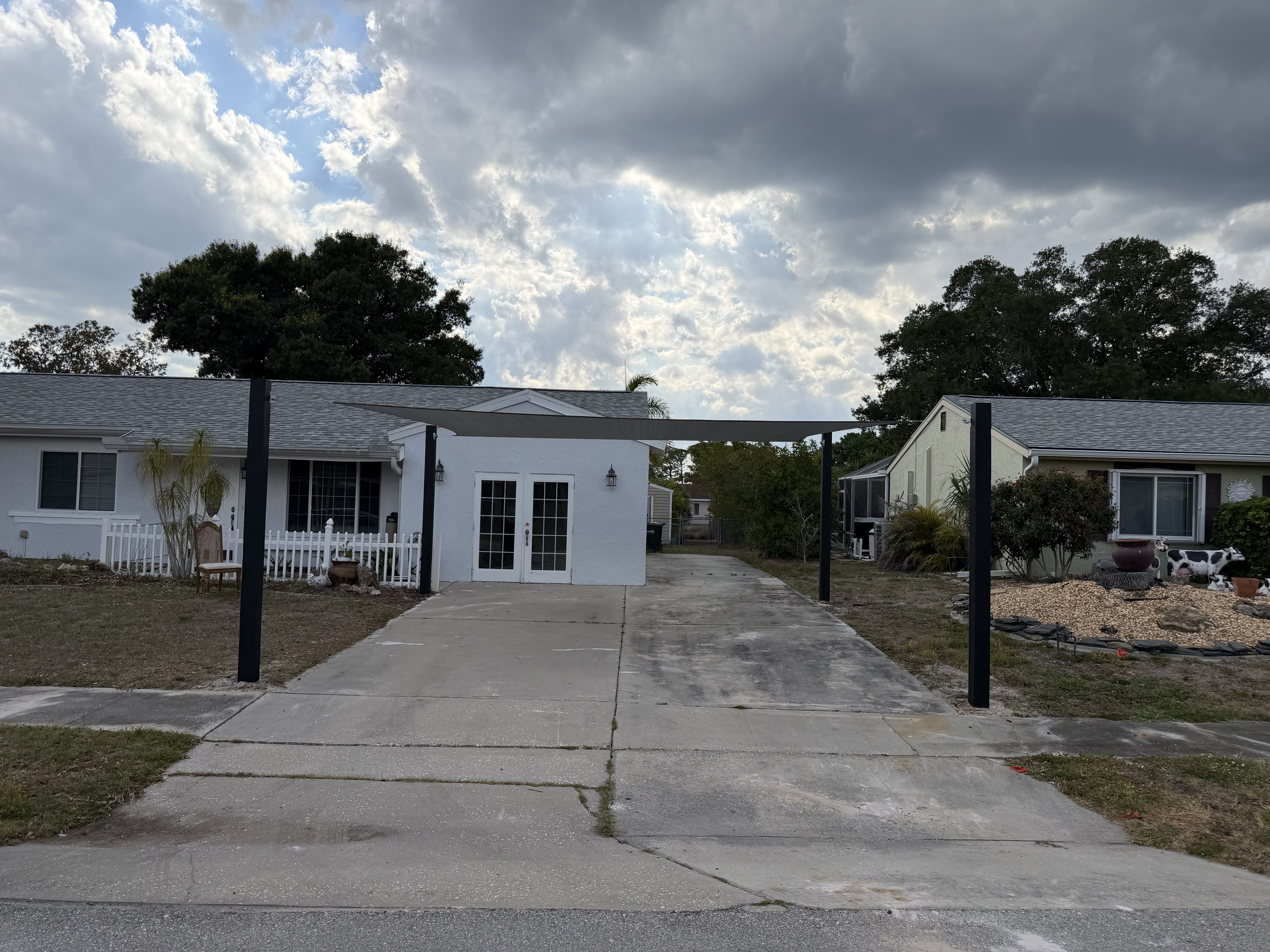 Driveway shade install with storm clouds